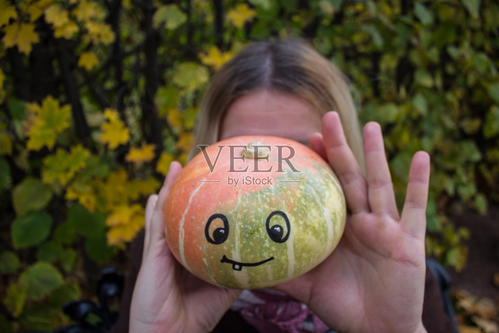 一个女人手里拿着一个南瓜，还有一张滑稽的脸照片摄影图片