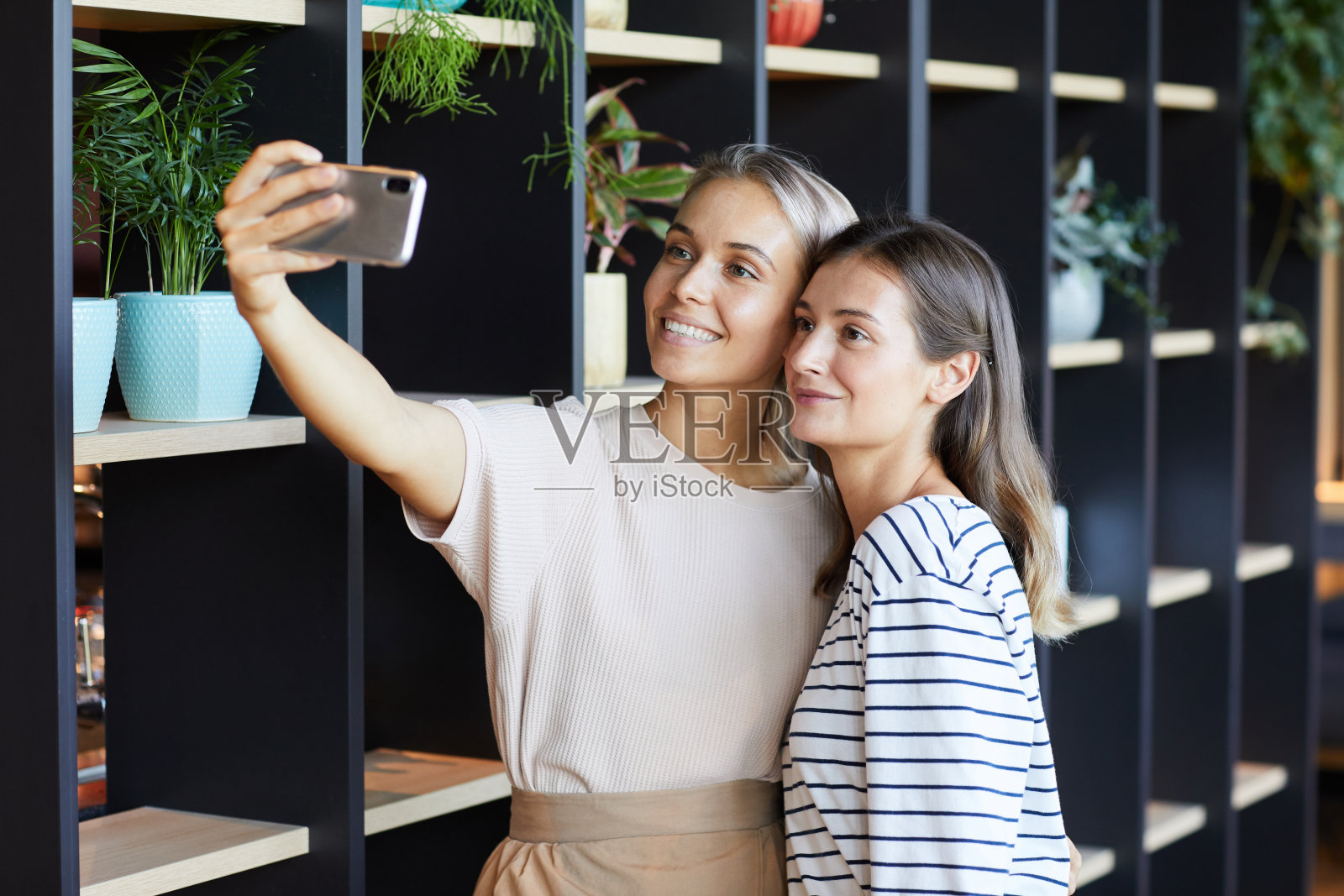 微笑迷人的年轻女子与漂亮的牙齿微笑与朋友在现代咖啡馆自拍照片摄影图片