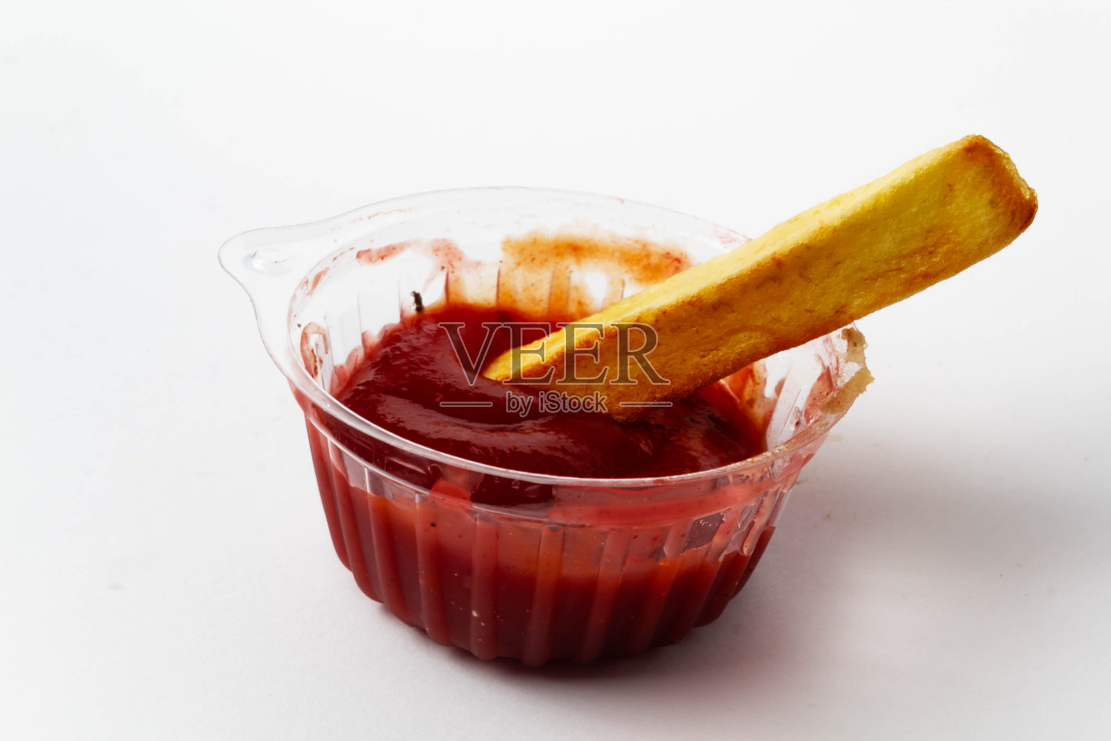 番茄酱装在塑料酱碟里，薯条放在白色的背景上照片摄影图片