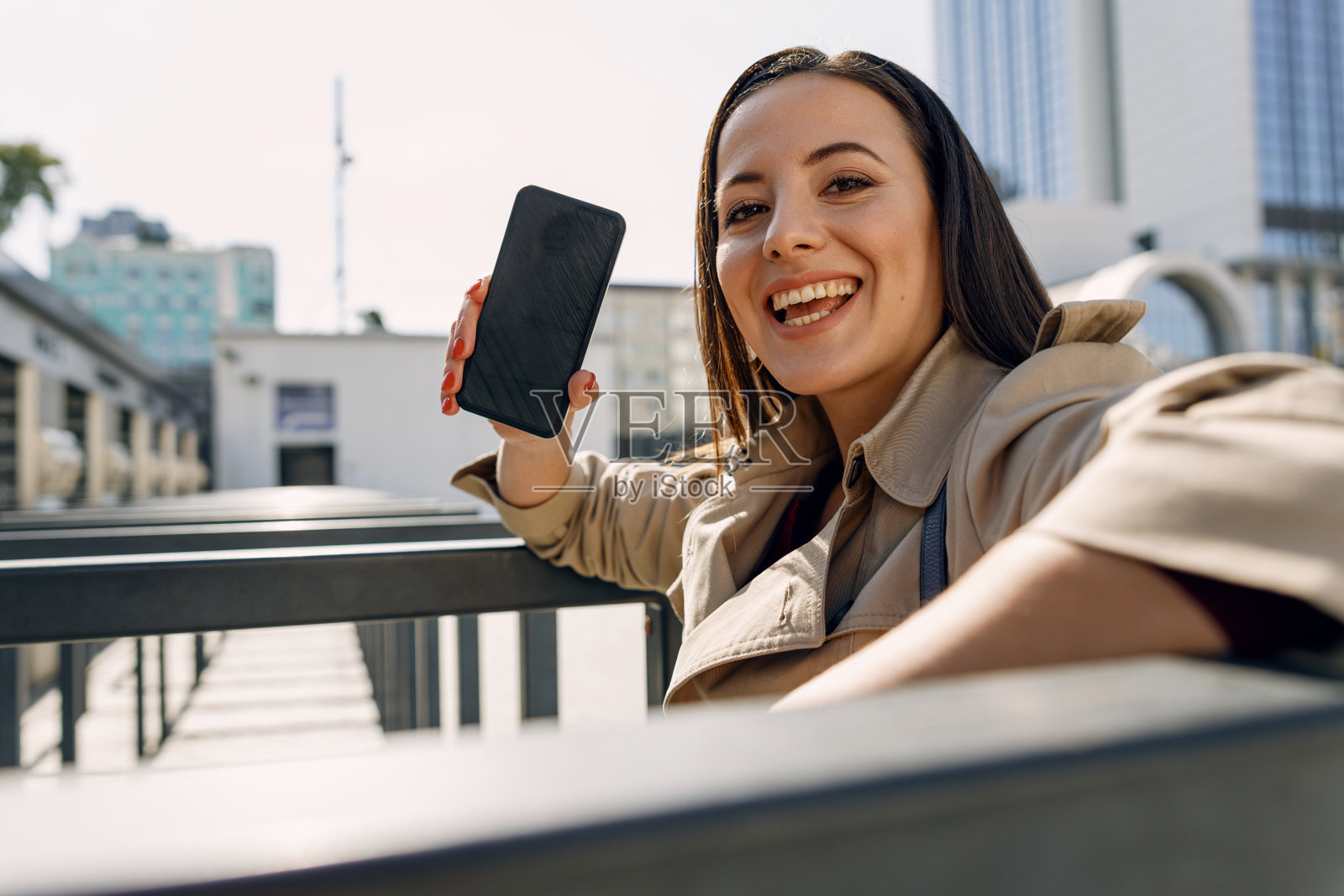 漂亮的黑发女性展示她的新智能手机照片摄影图片