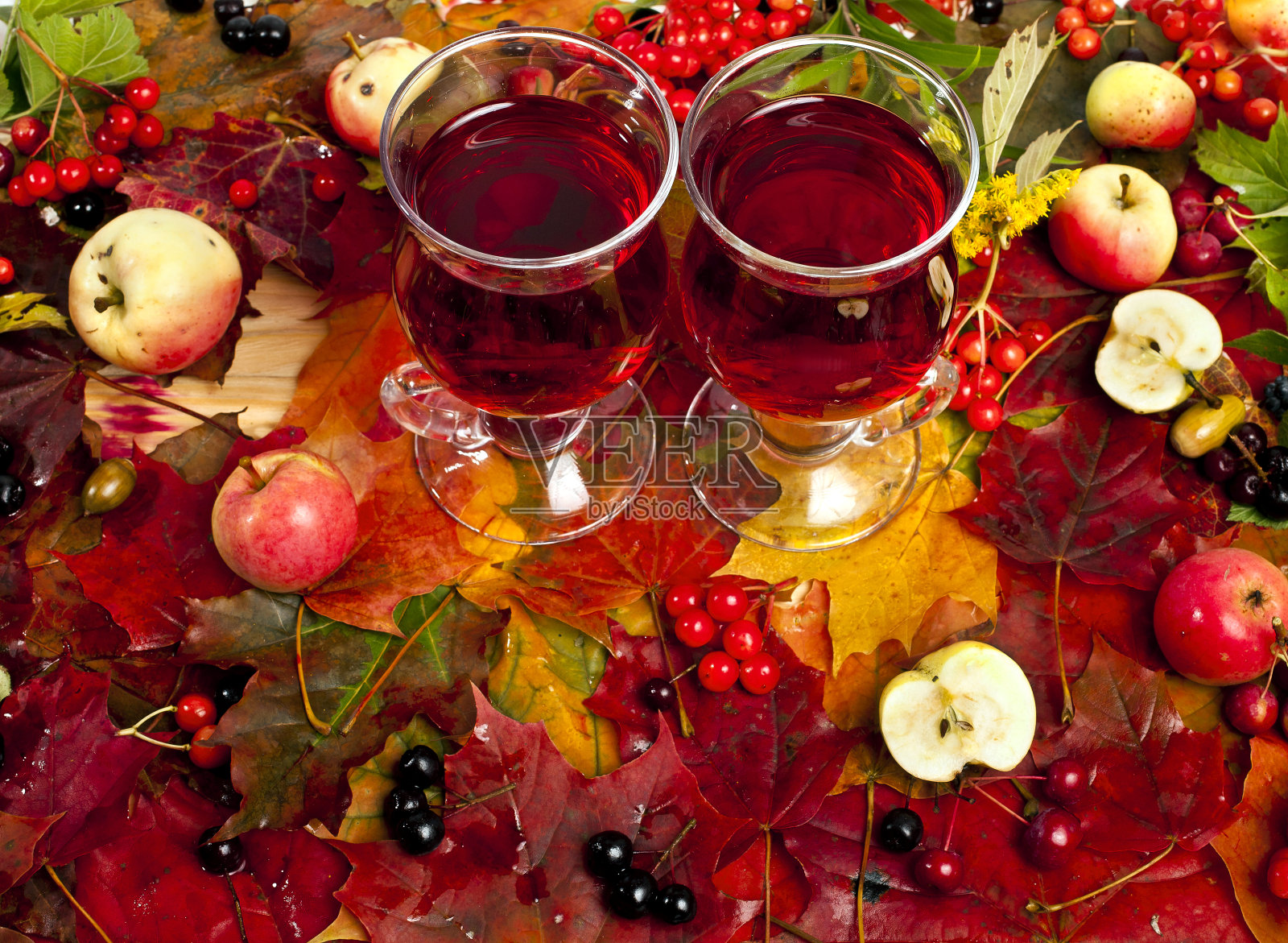 热红酒在秋叶、浆果和苹果的背景下照片摄影图片