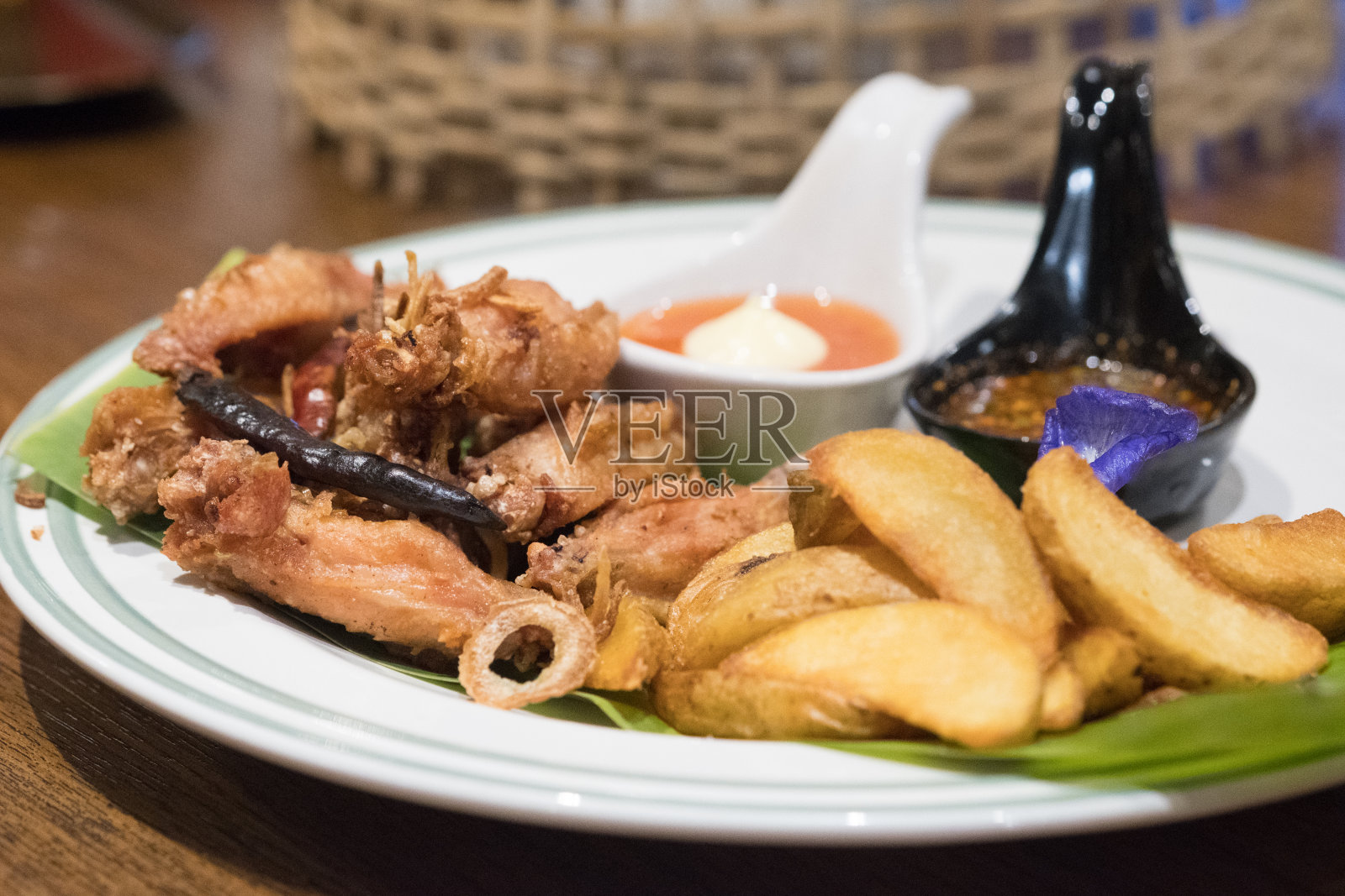 炸鸡腿、翅膀和炸薯条配芭蕉叶照片摄影图片