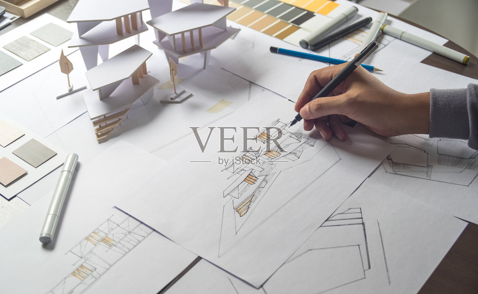 在建筑师工作室进行建筑设计施工图、草图、设计图和建筑施工模型的制作照片摄影图片