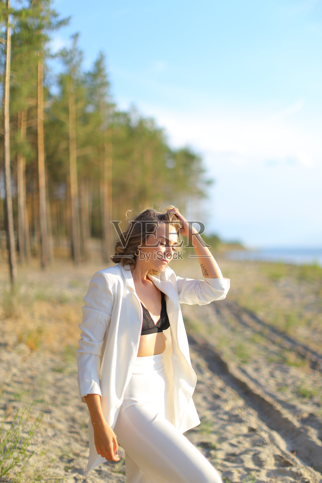 漂亮的白人女孩走在沙滩上，穿着白色的衣服照片摄影图片