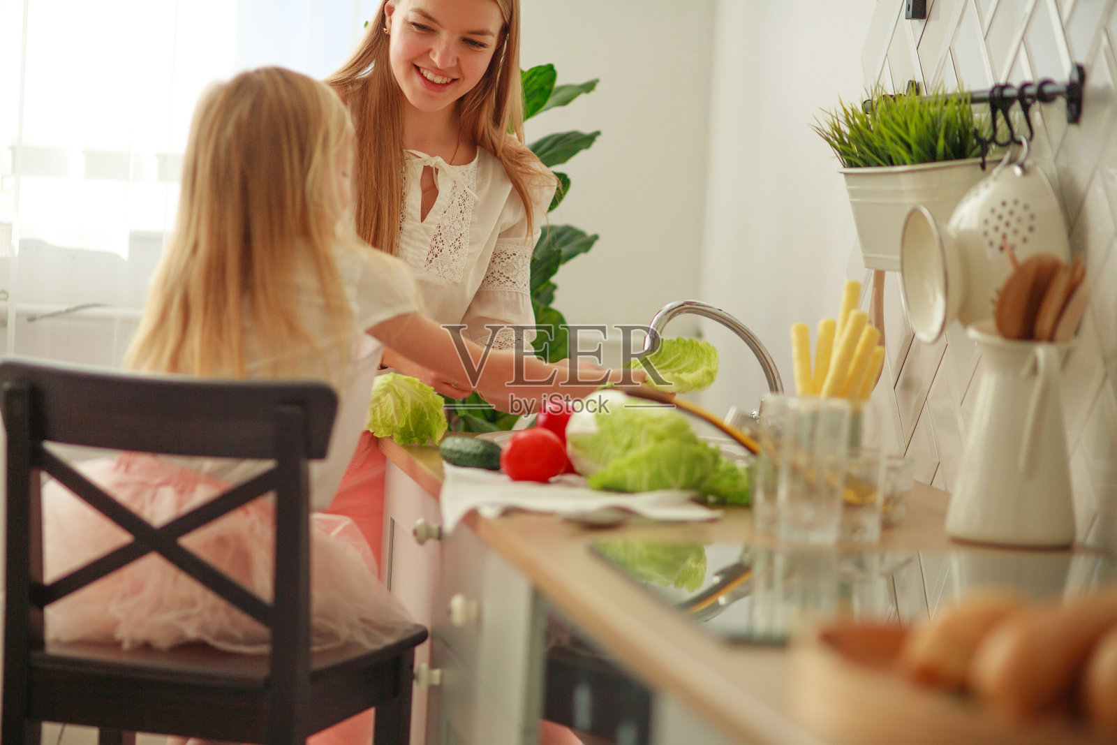 快乐年轻的母亲和女儿在厨房洗菜槽，孩子和父母在家里互动，健康的生活方式照片摄影图片