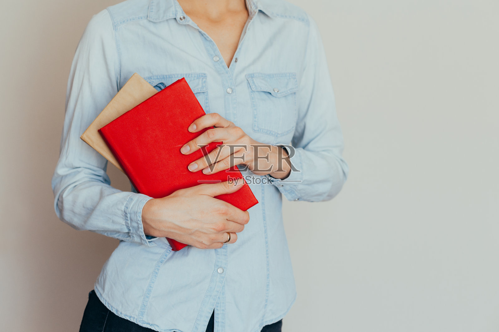 在房间里，一双美丽的女性的手拿着一本打开的书或杂志，靠在一面墙上照片摄影图片