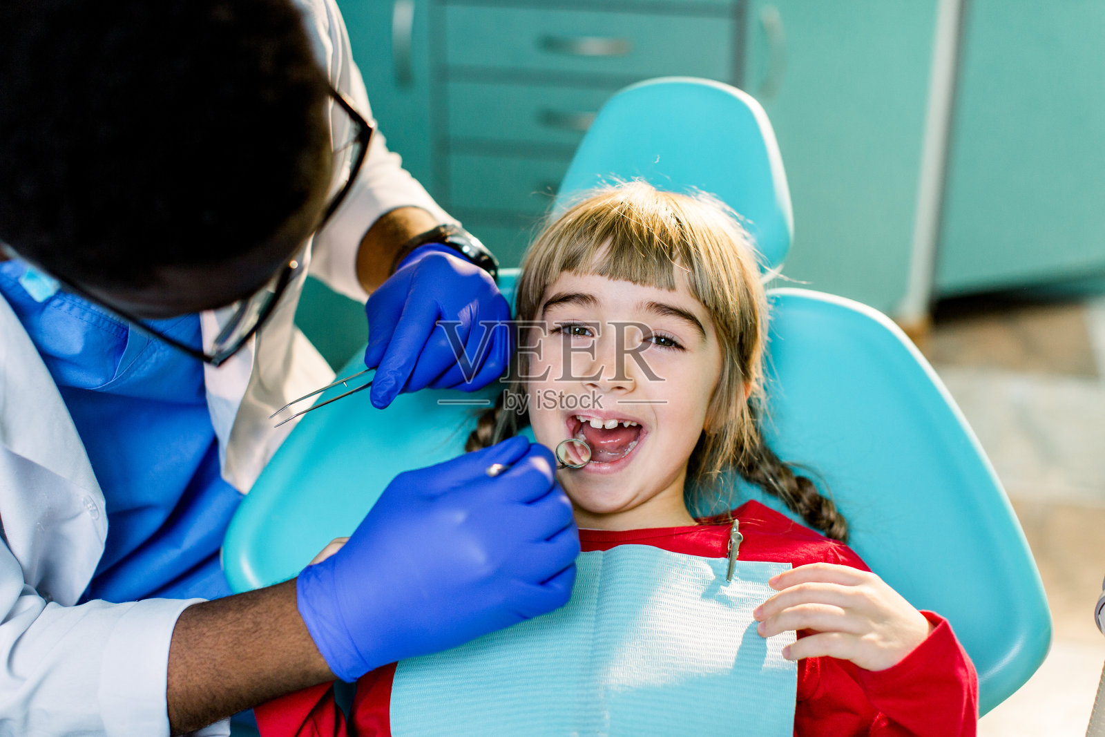 可爱的微笑的女孩坐在牙医的扶手椅照片摄影图片