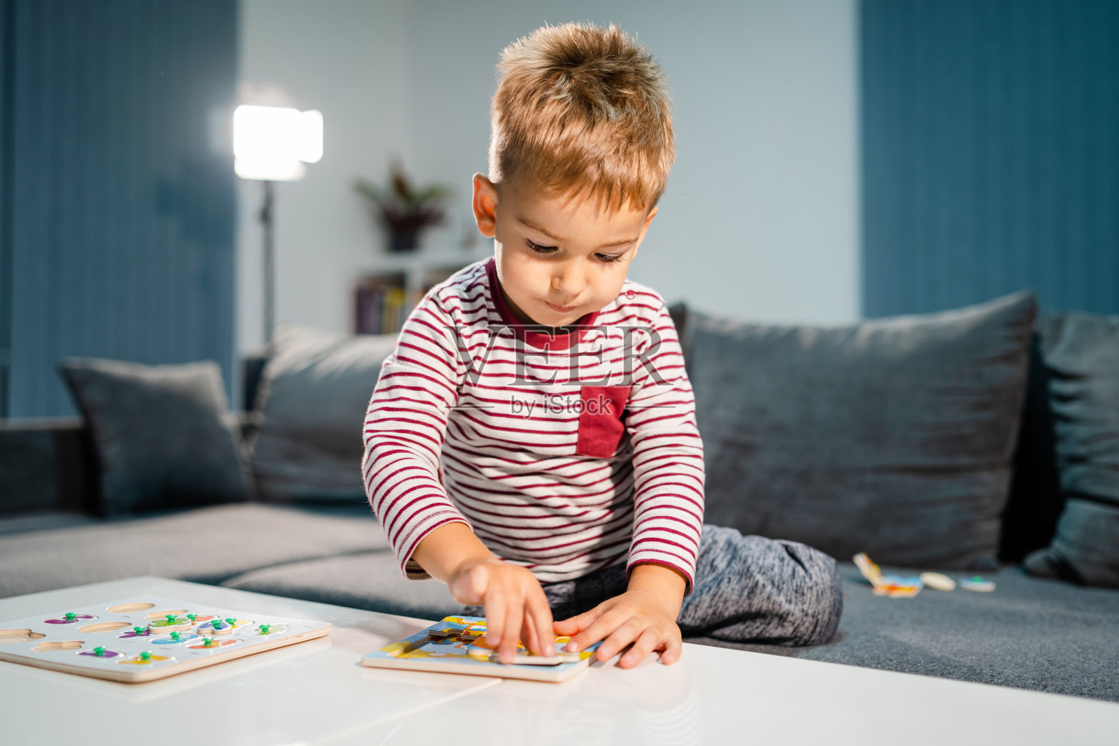 小男孩独自在家玩小游戏，在桌子旁玩拼图，发展智力，有乐趣的学习照片摄影图片