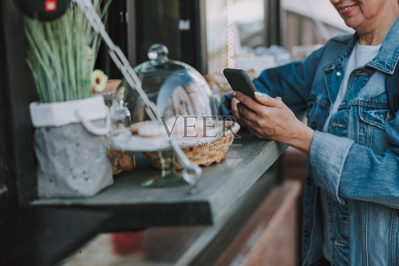 一个拿着智能手机站在售货亭旁边的女人照片摄影图片
