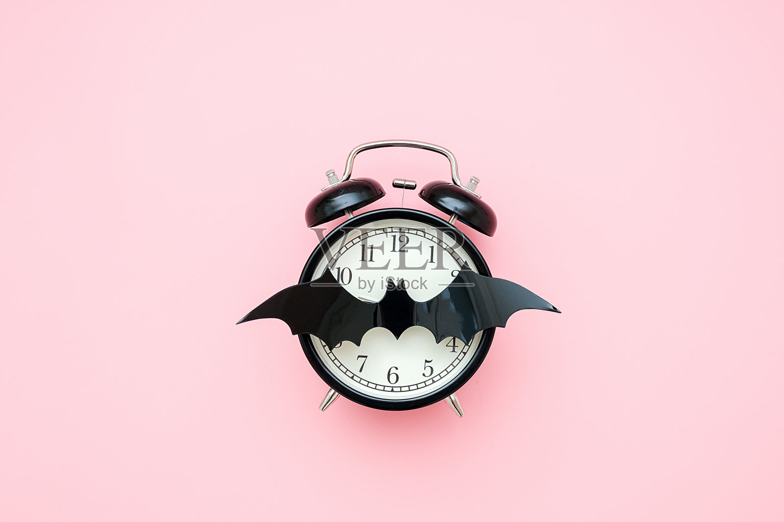 万圣节之夜的概念。黑色闹钟和球棒上的脸钟在粉红色的背景。创意平铺，俯视图，复制空间，模板为您的设计，贺卡，邀请照片摄影图片