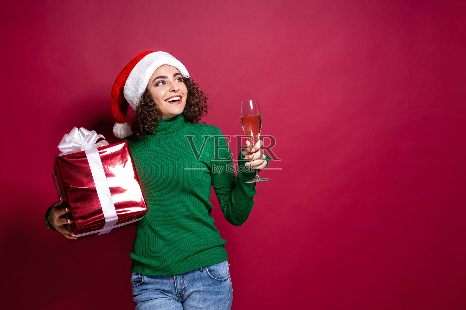 美丽时尚的女人在圣诞老人的帽子。温暖的圣诞毛衣，抱着礼盒照片摄影图片