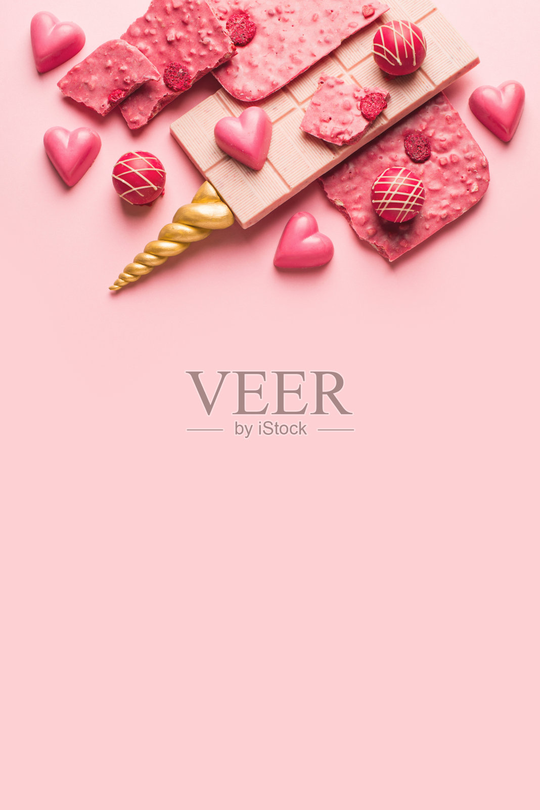 粉色的巧克力条，上面有金色的独角兽角。照片摄影图片