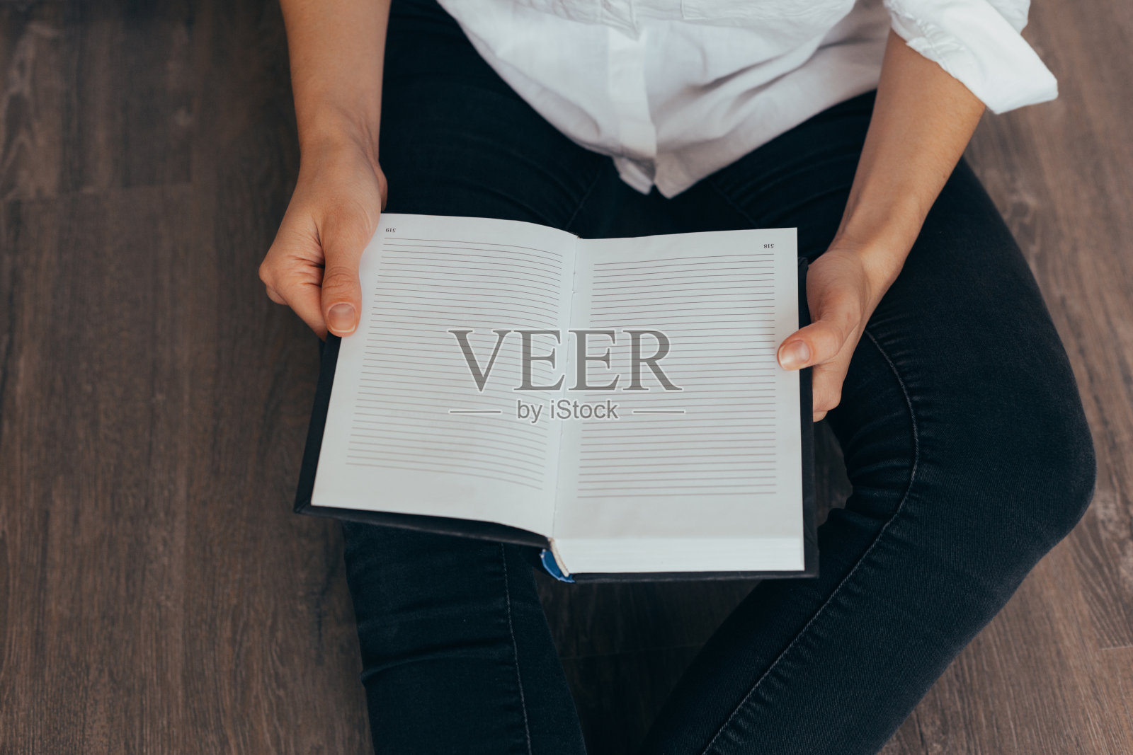 在房间的黑色沙发上，美丽的女性手拿着一本打开的书或杂志照片摄影图片