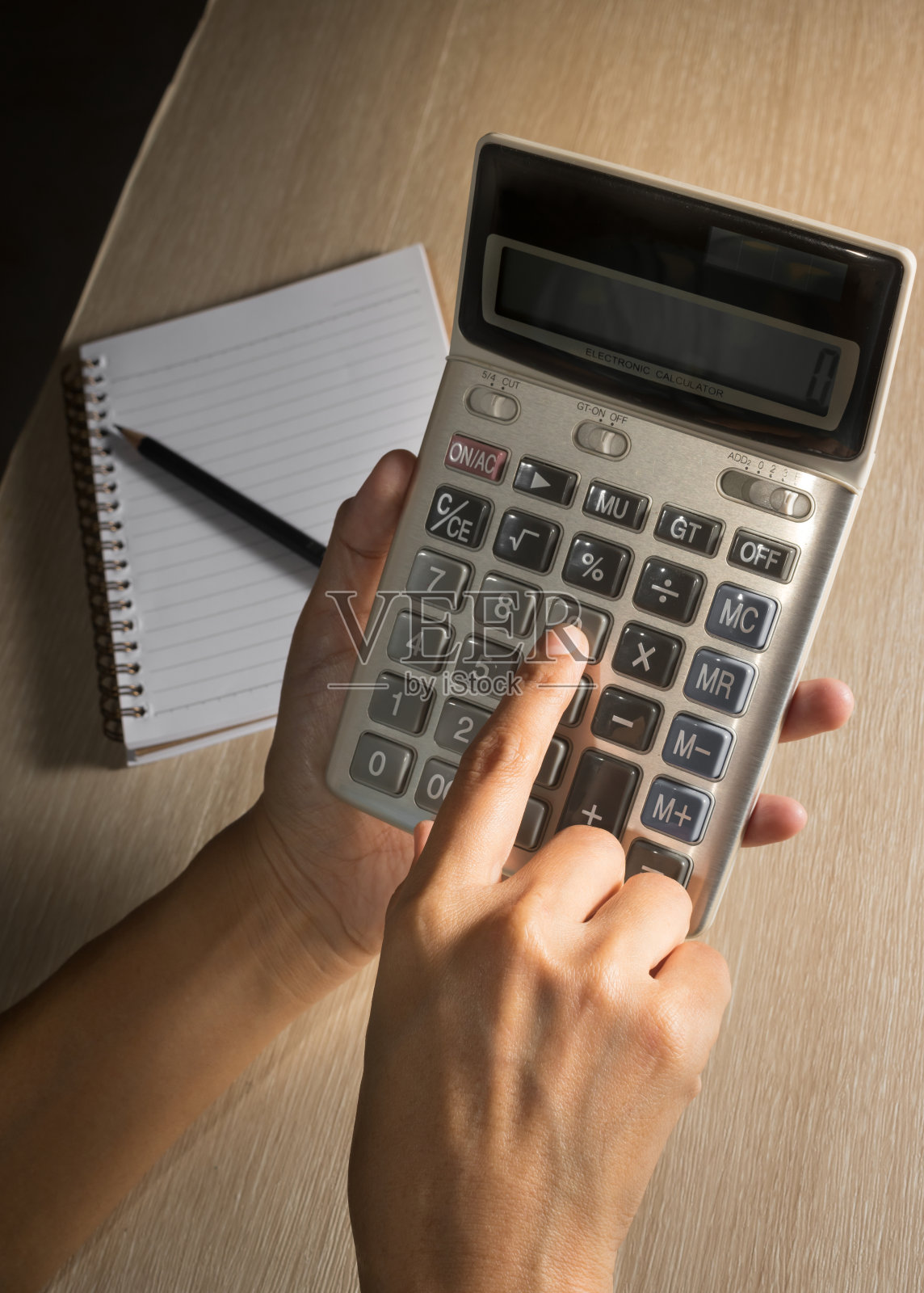 女人手里拿着铅笔和书用计算器。照片摄影图片