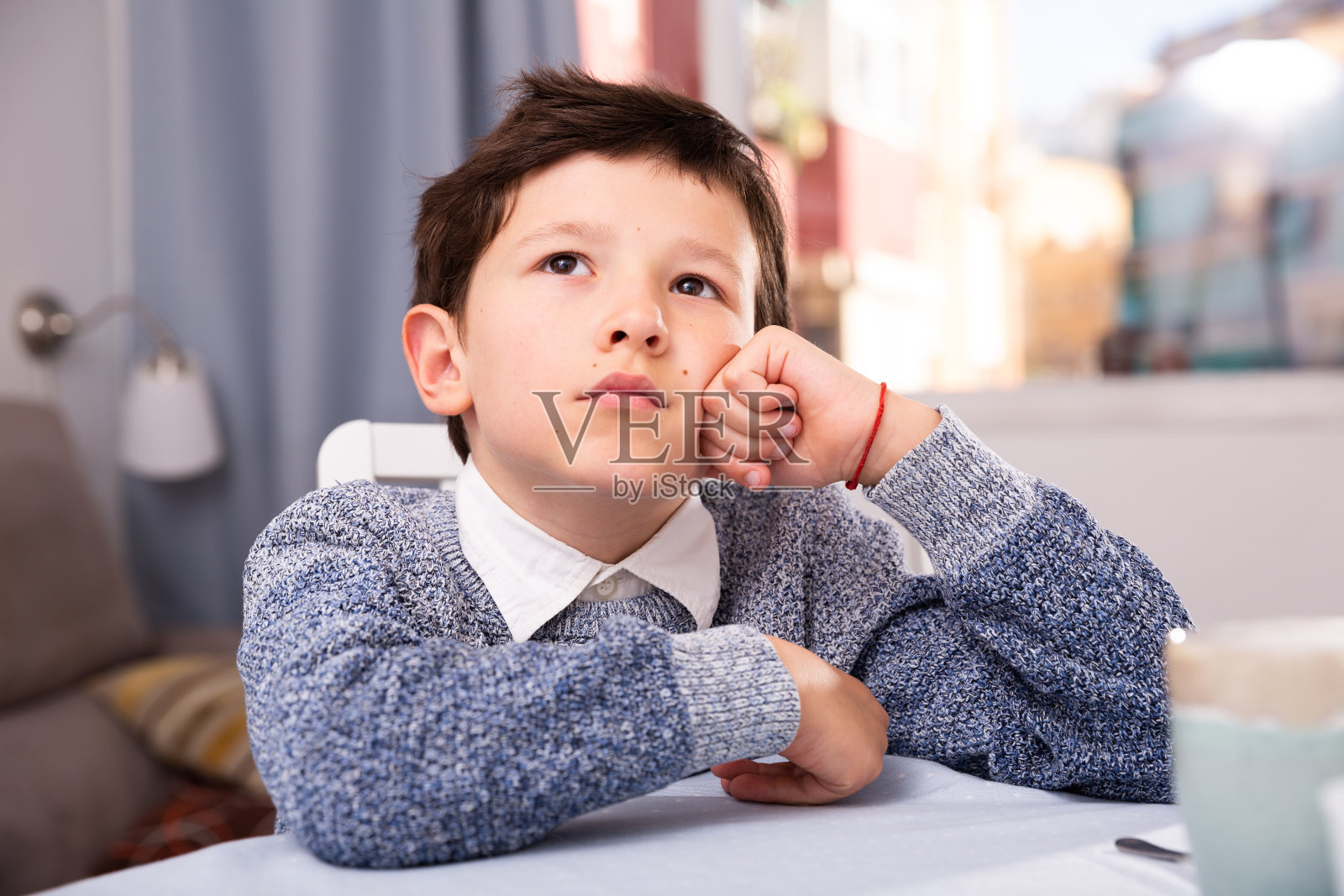 心烦意乱的男孩坐在桌子旁思考问题照片摄影图片