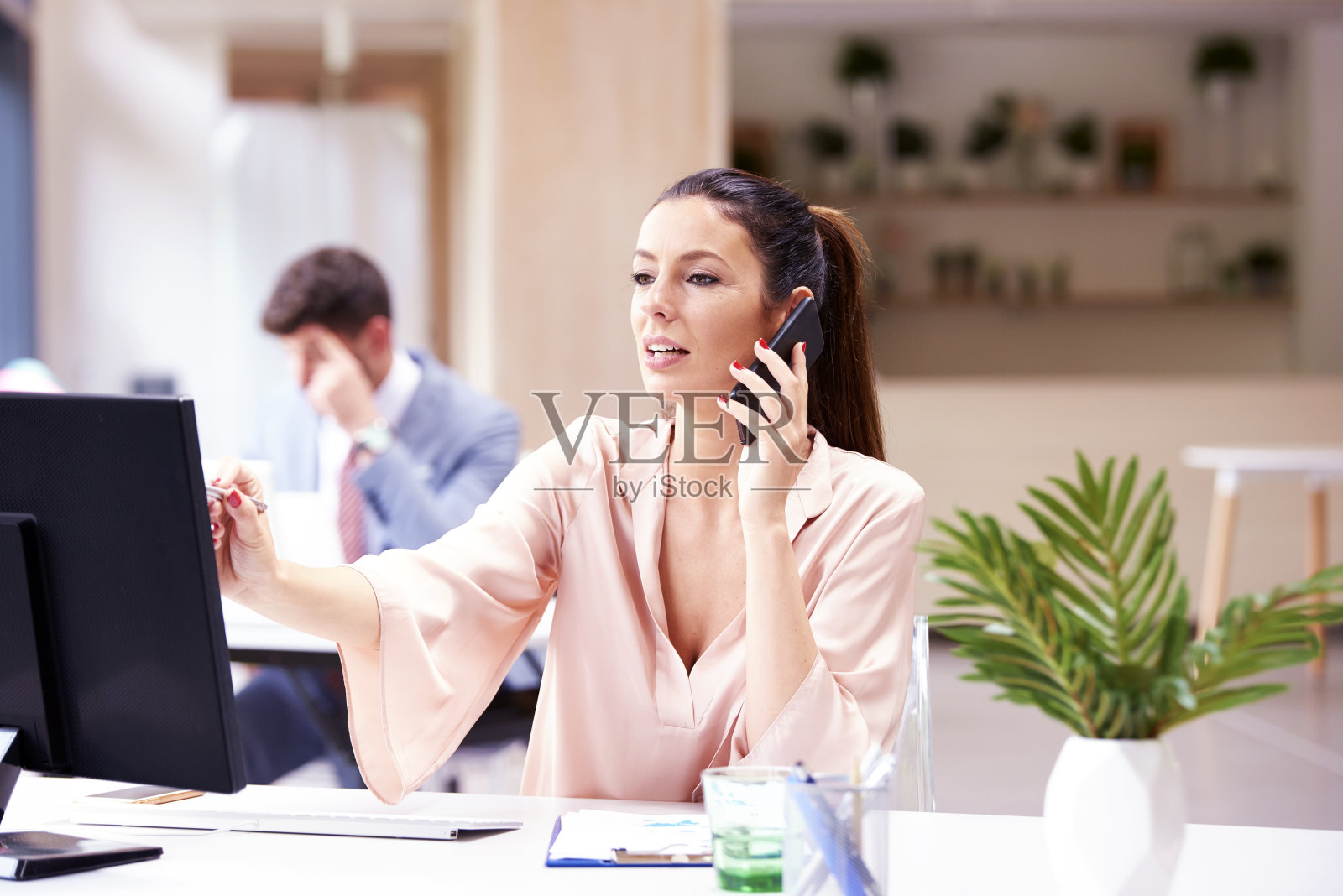 投资顾问女商人一边在办公室用电脑工作一边打电话照片摄影图片