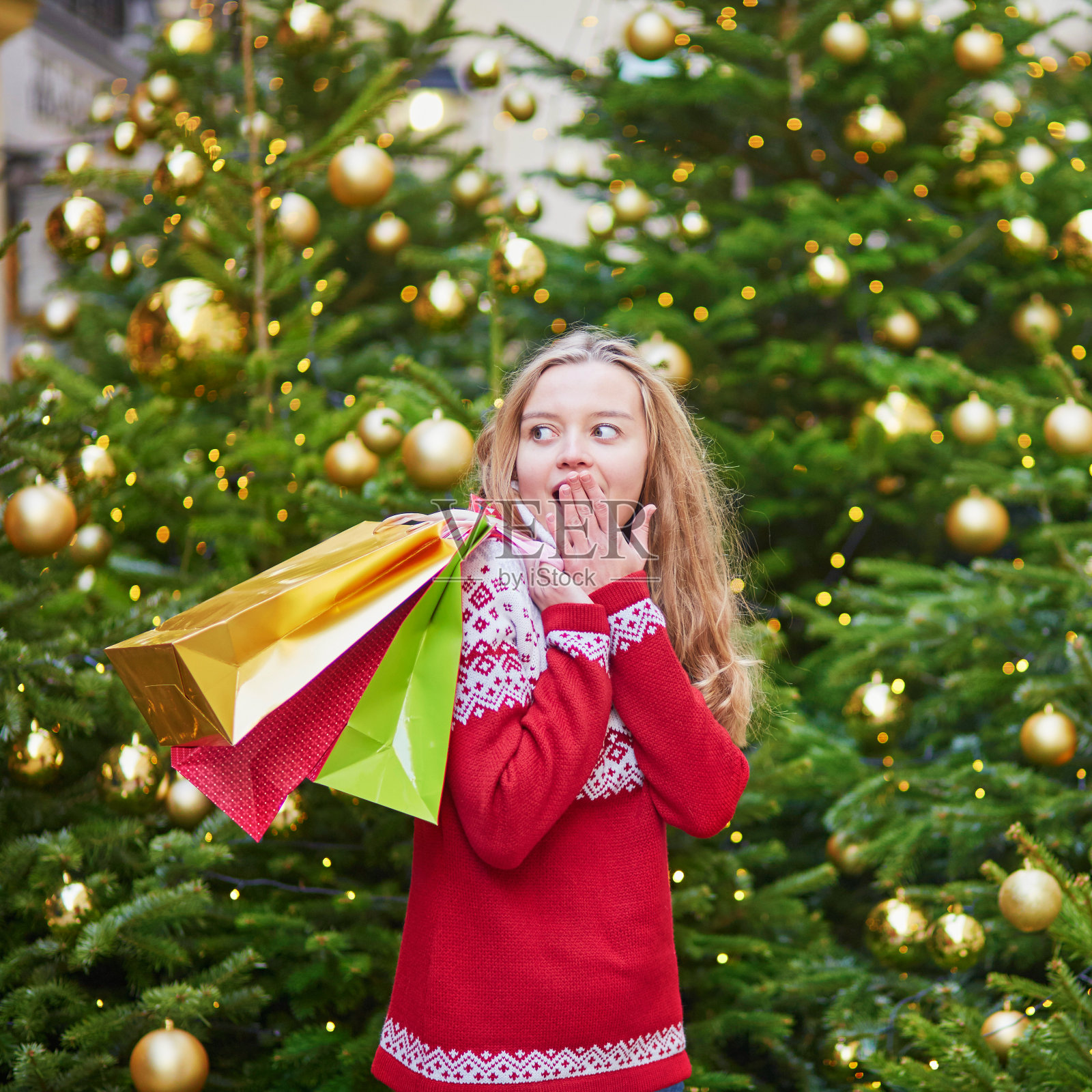 拿着彩色购物袋的女孩在圣诞树旁照片摄影图片