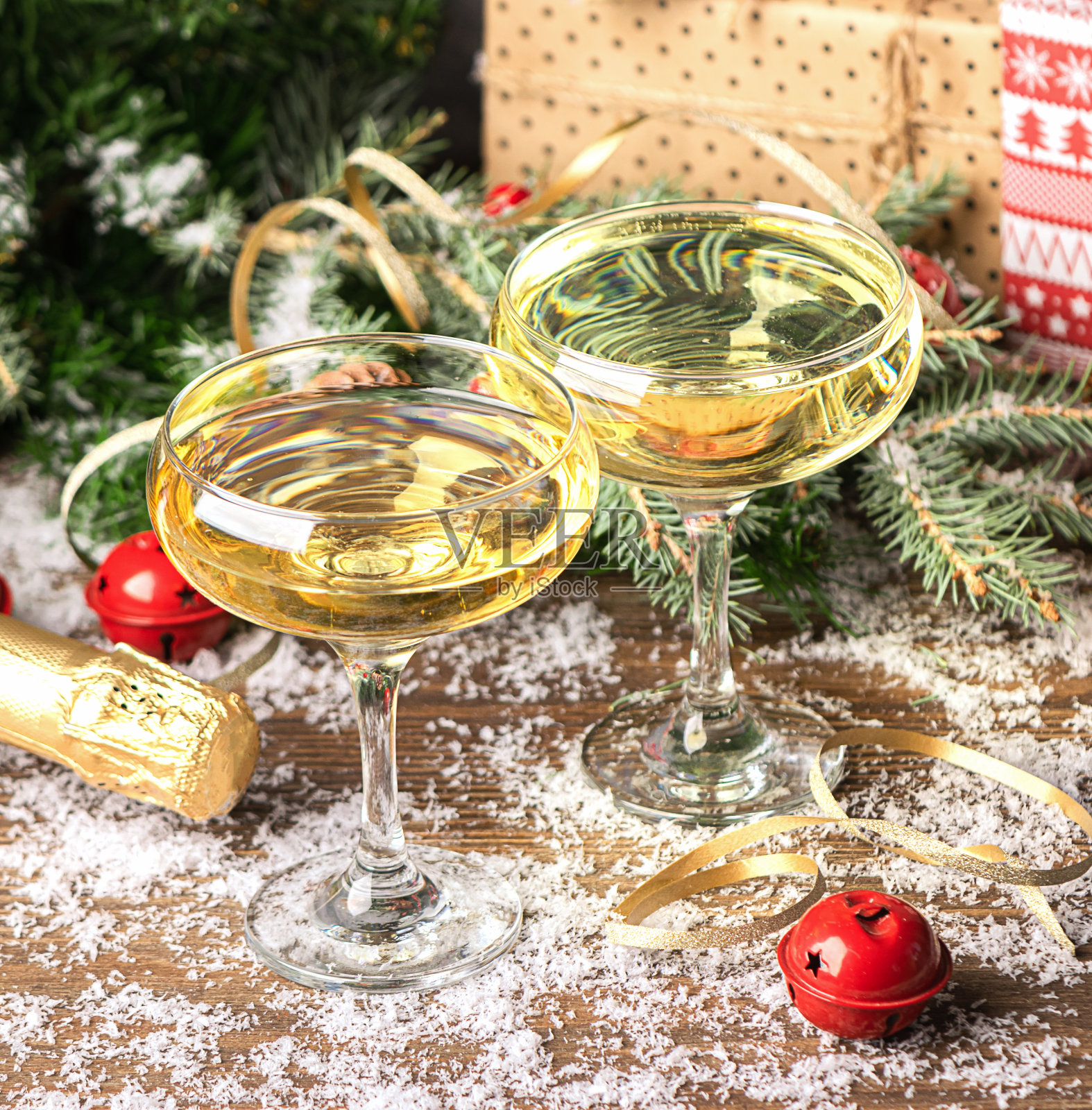 两杯香槟起泡酒的特写软木塞在圣诞装饰的桌子上。新年的概念。照片摄影图片