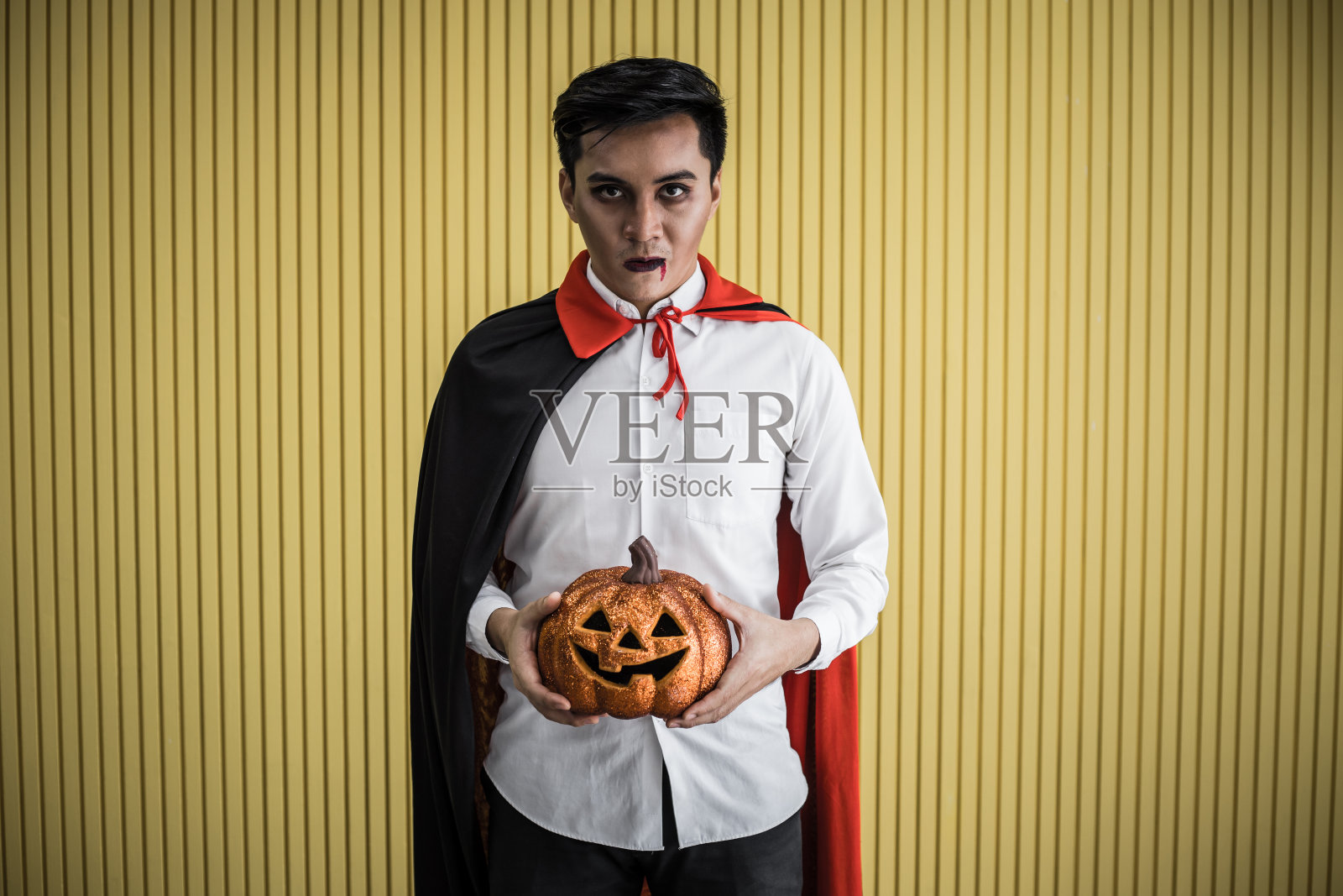 黄色背景下的年轻亚洲德古拉装扮男人照片摄影图片