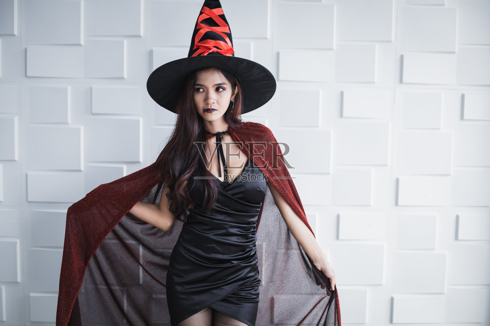 穿着戏服的年轻亚洲女人，白墙上的女巫。照片摄影图片