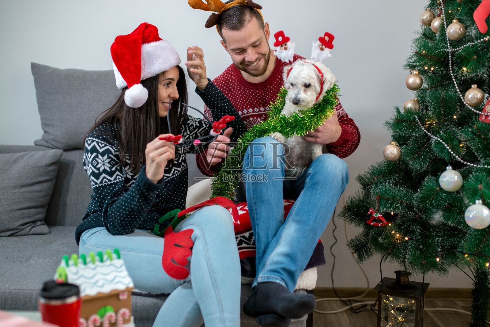 快乐的夫妇在家里装饰圣诞树。微笑的男人和女人一起庆祝圣诞节或新年。圣诞树装饰。家庭照片摄影图片