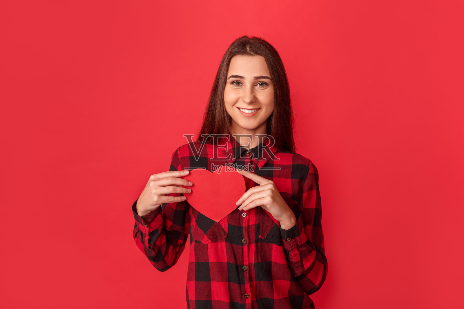 情人节。年轻女子孤立地站在红心卡片上，开心地对着镜头微笑照片摄影图片