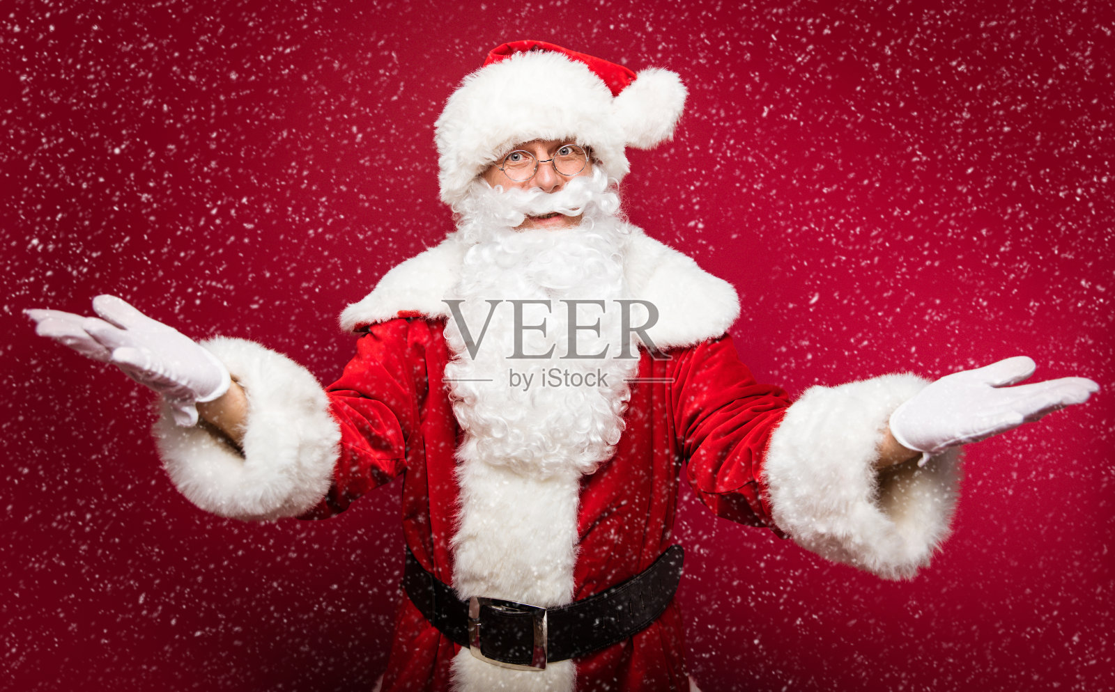 圣诞节和新年的概念。快乐美丽的圣诞老人在红色的服装是摆出蓝色的冬天背景。照片摄影图片