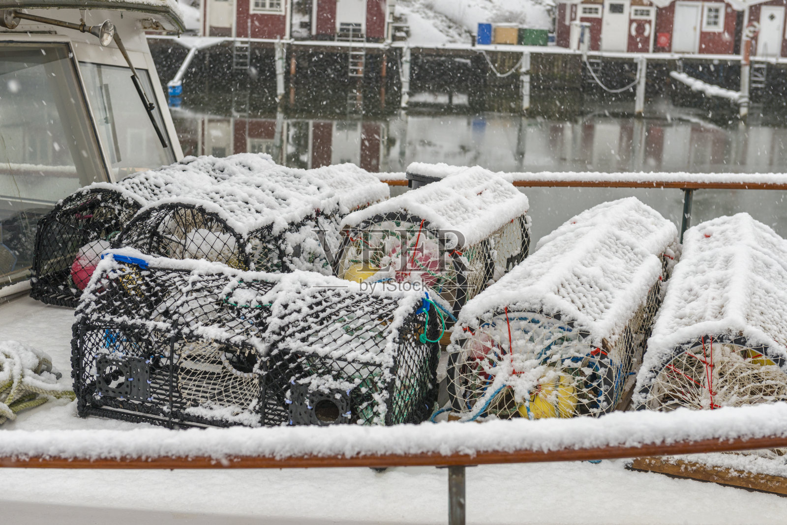 被雪覆盖的船甲板上的龙虾陷阱照片摄影图片