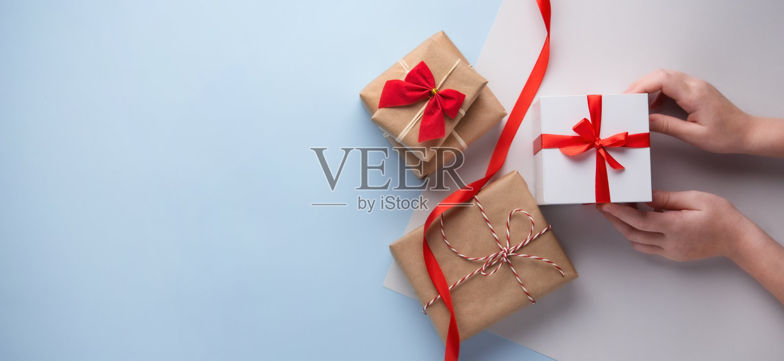 圣诞平放与手握盒子礼物在蓝色的背景。俯视图照片摄影图片