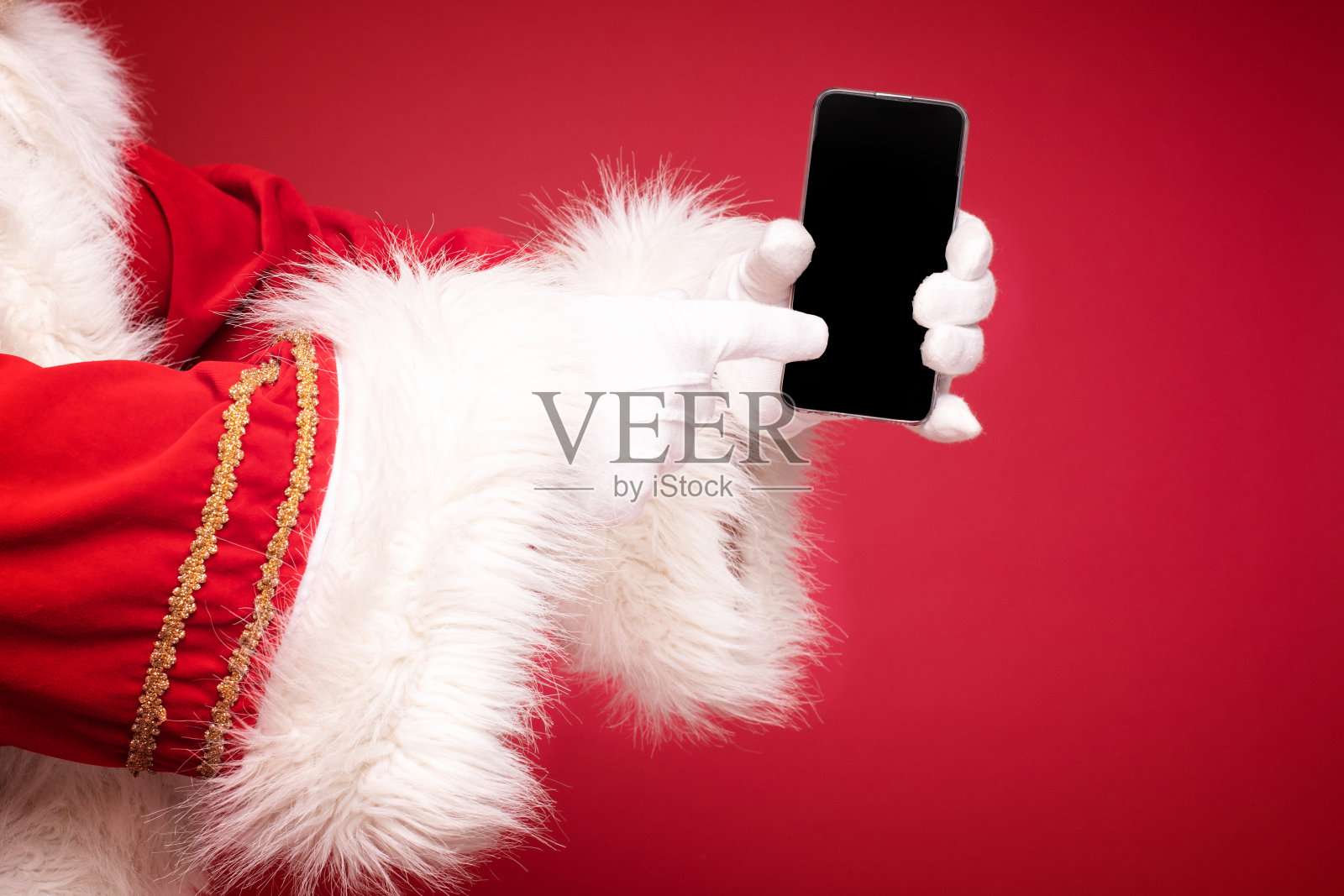 圣诞老人手牵着手机。照片摄影图片