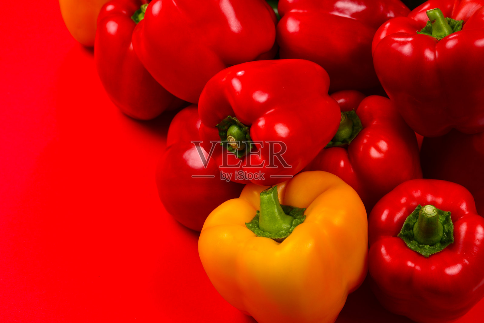 鲜红、黄、绿的甜椒在红色背景上。照片摄影图片