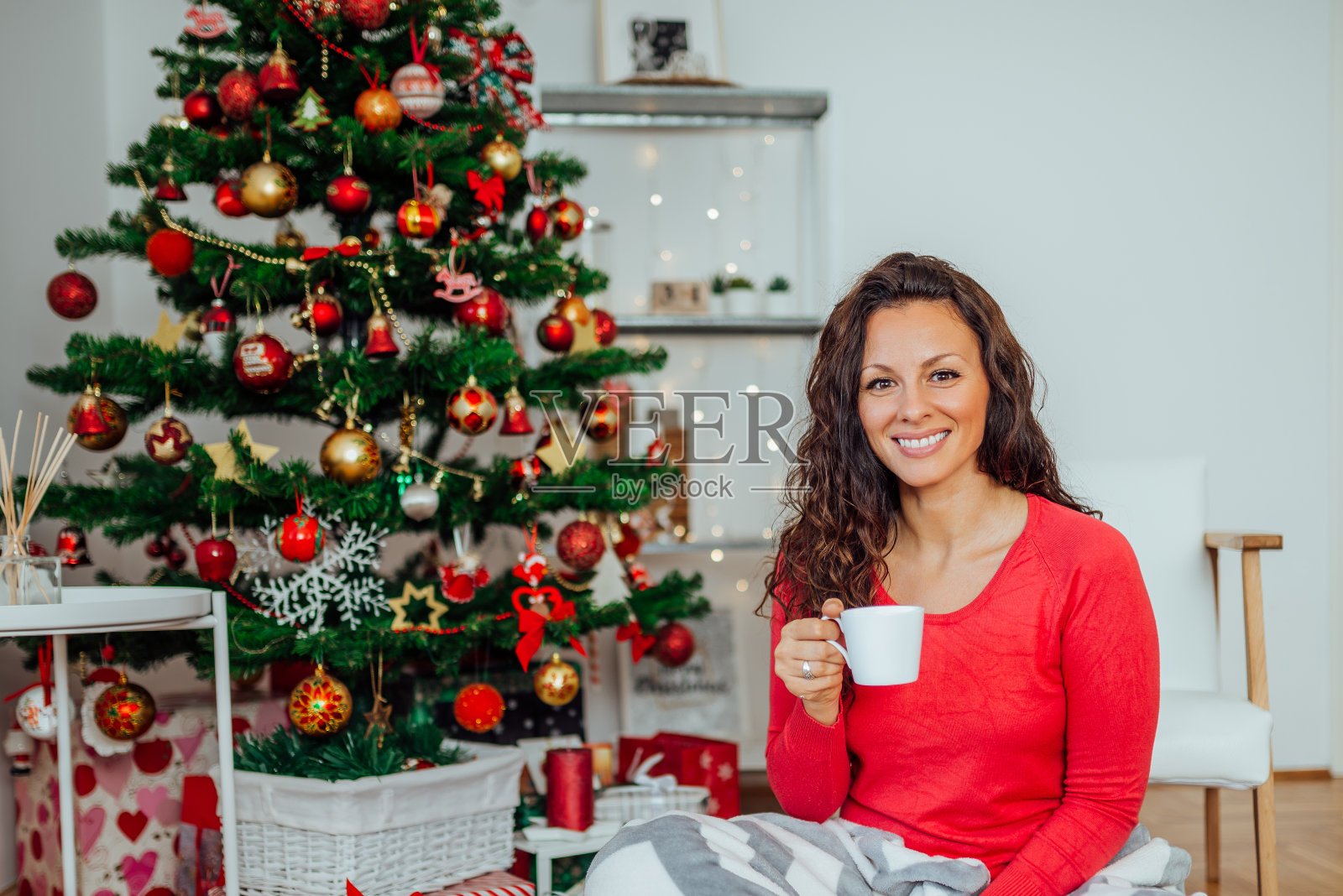 一个美丽的年轻女人在圣诞节期间在舒适的家里喝茶的肖像。照片摄影图片