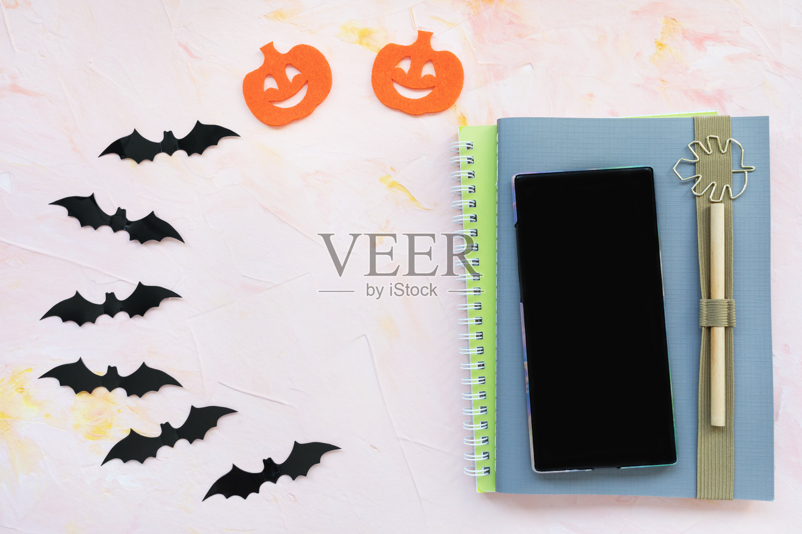 笔记本，笔，南瓜，蝙蝠和一个手机背景。万圣节的概念。照片摄影图片