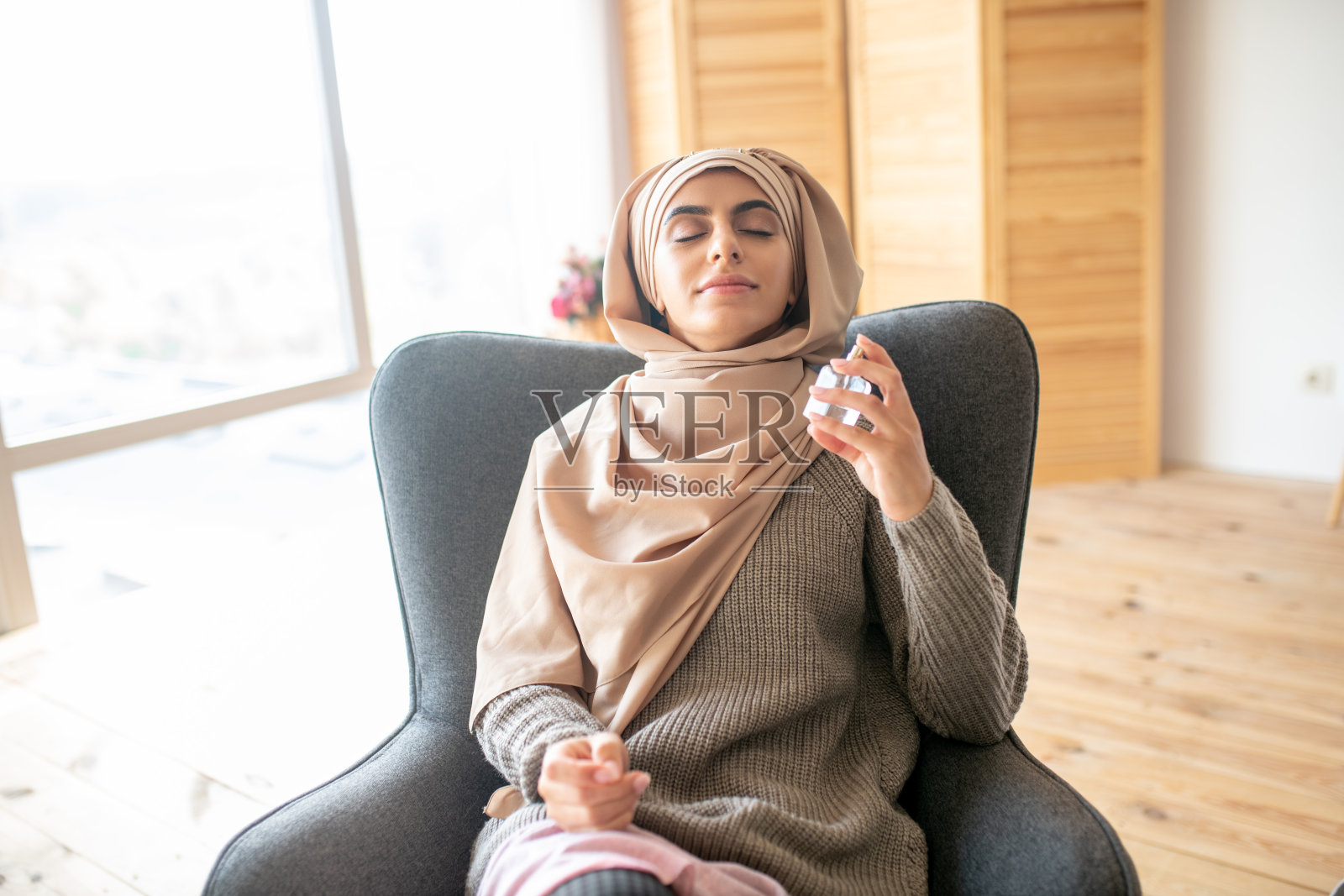 坐在椅子上享受新香水味道的漂亮女人照片摄影图片