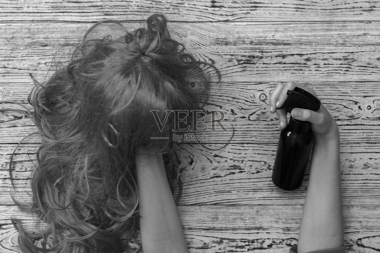 一个孩子的手拿着假发和发胶的黑白照片。照片摄影图片