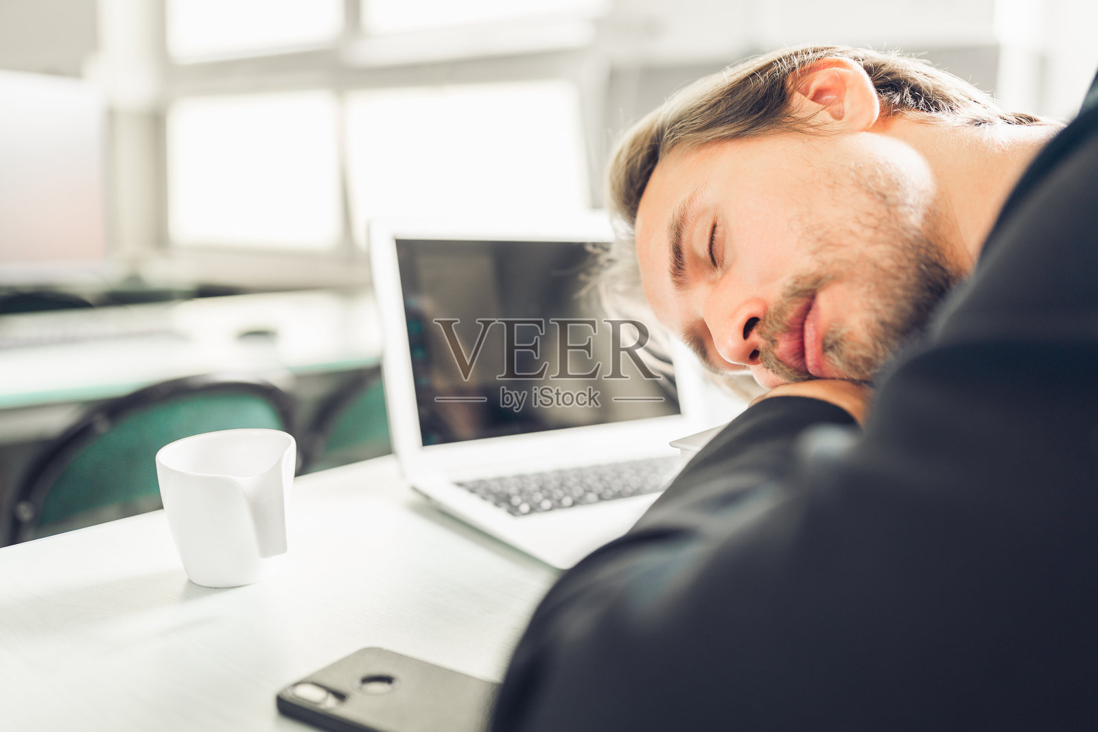 年轻人在他的桌子上睡觉。照片摄影图片