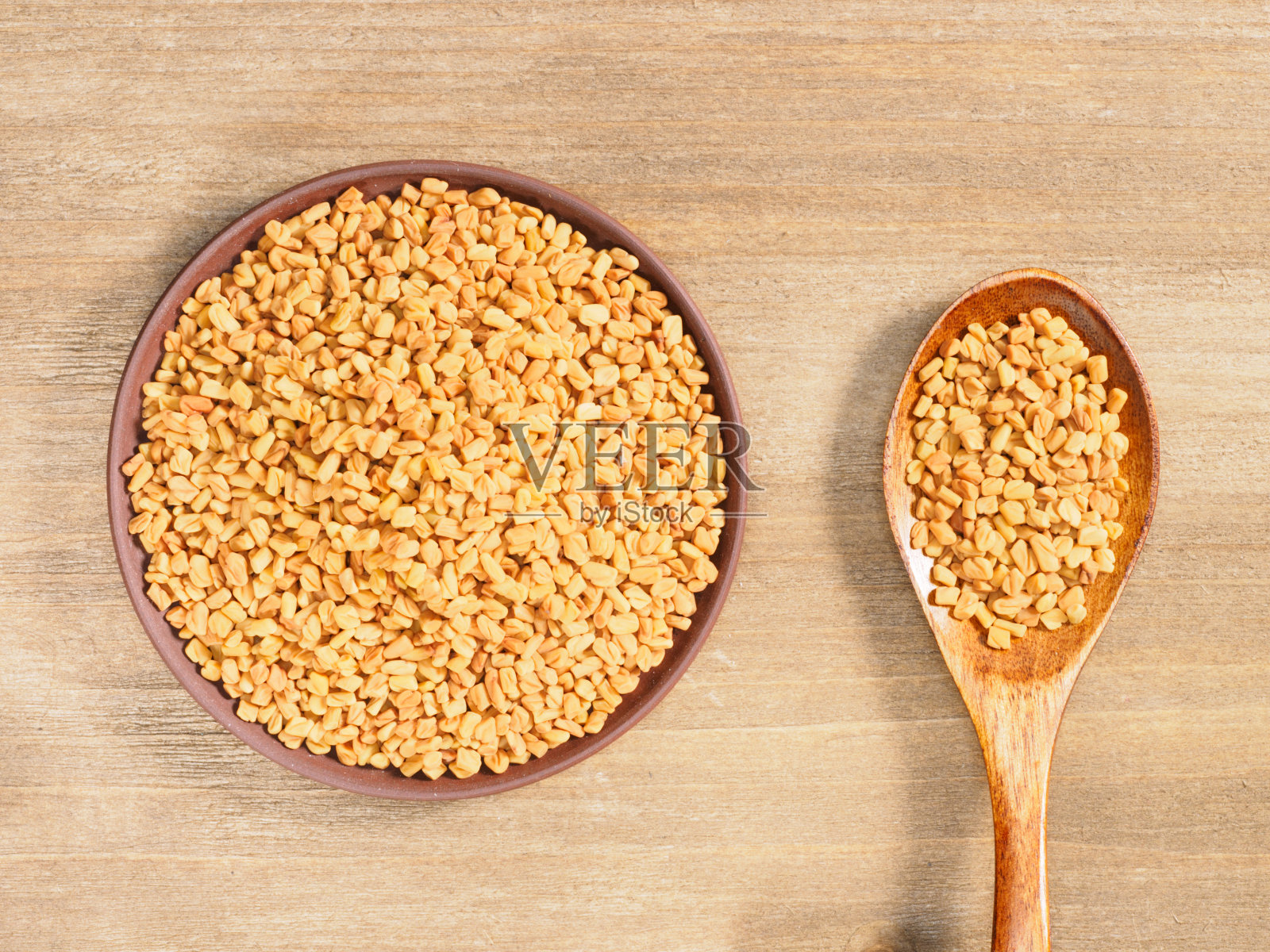 胡芦巴在粘土盘子和勺子在棕色的木制背景。印度烹饪，阿育吠陀，自然疗法，现代医药概念照片摄影图片