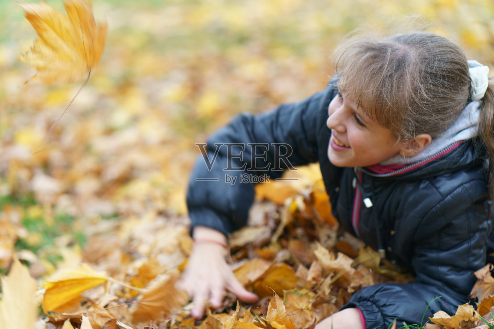 女孩在城市公园里玩着金色的秋叶照片摄影图片