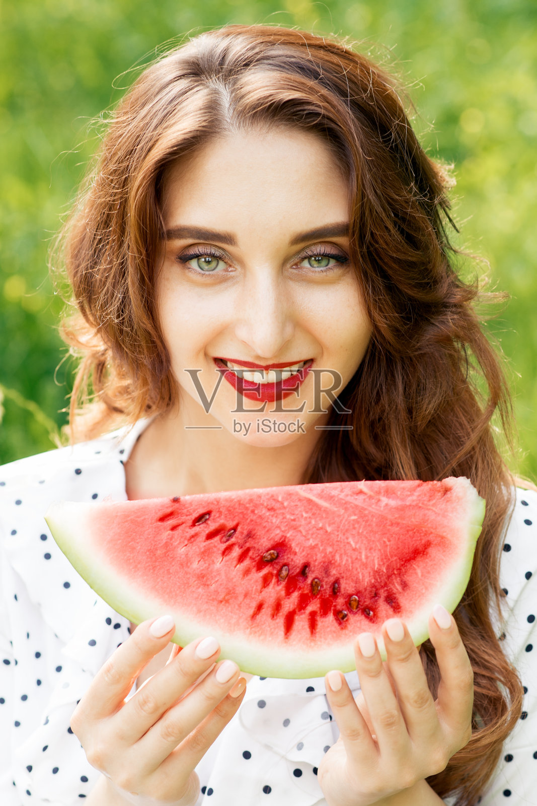 一个美丽的微笑女人的肖像拿着一片西瓜。照片摄影图片