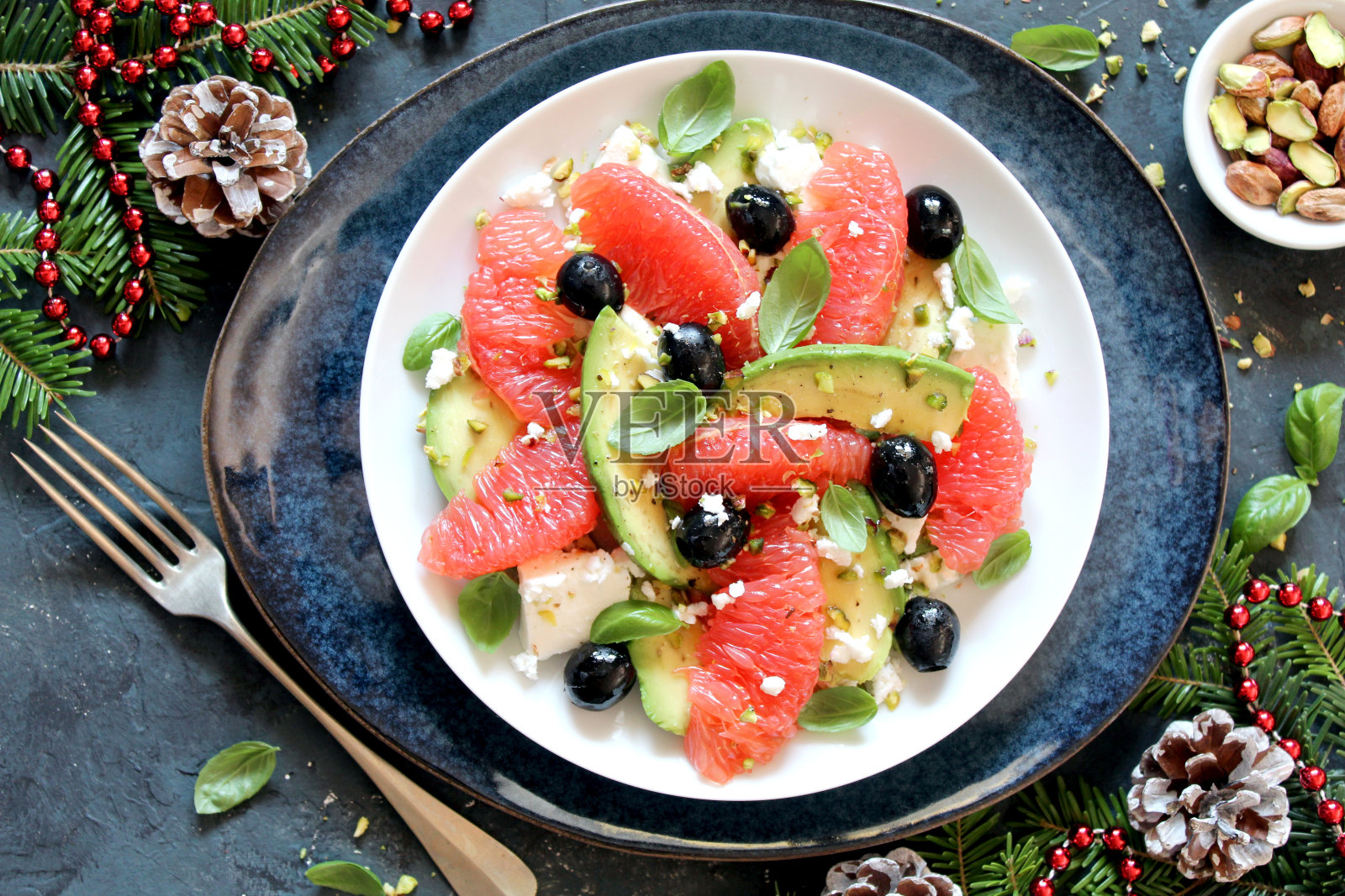 圣诞沙拉配牛油果、葡萄柚、羊乳酪、黑橄榄和开心果。照片摄影图片