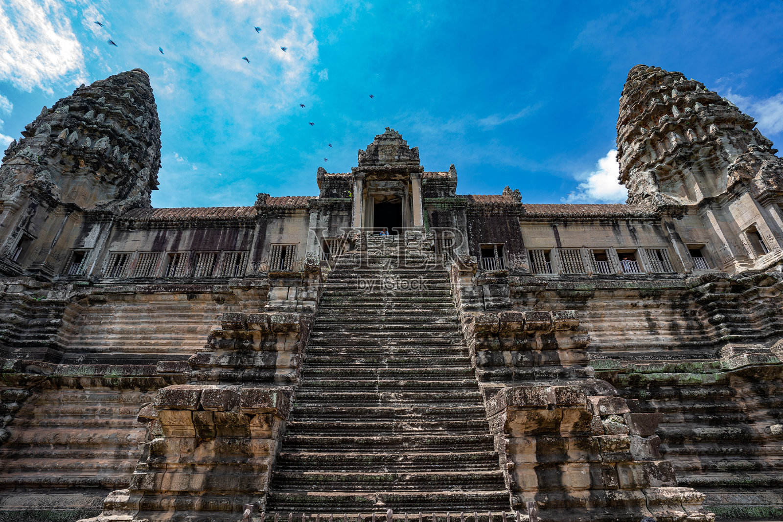吴哥窟寺庙中不知名的人物，有楼梯、塔和飞鸟照片摄影图片