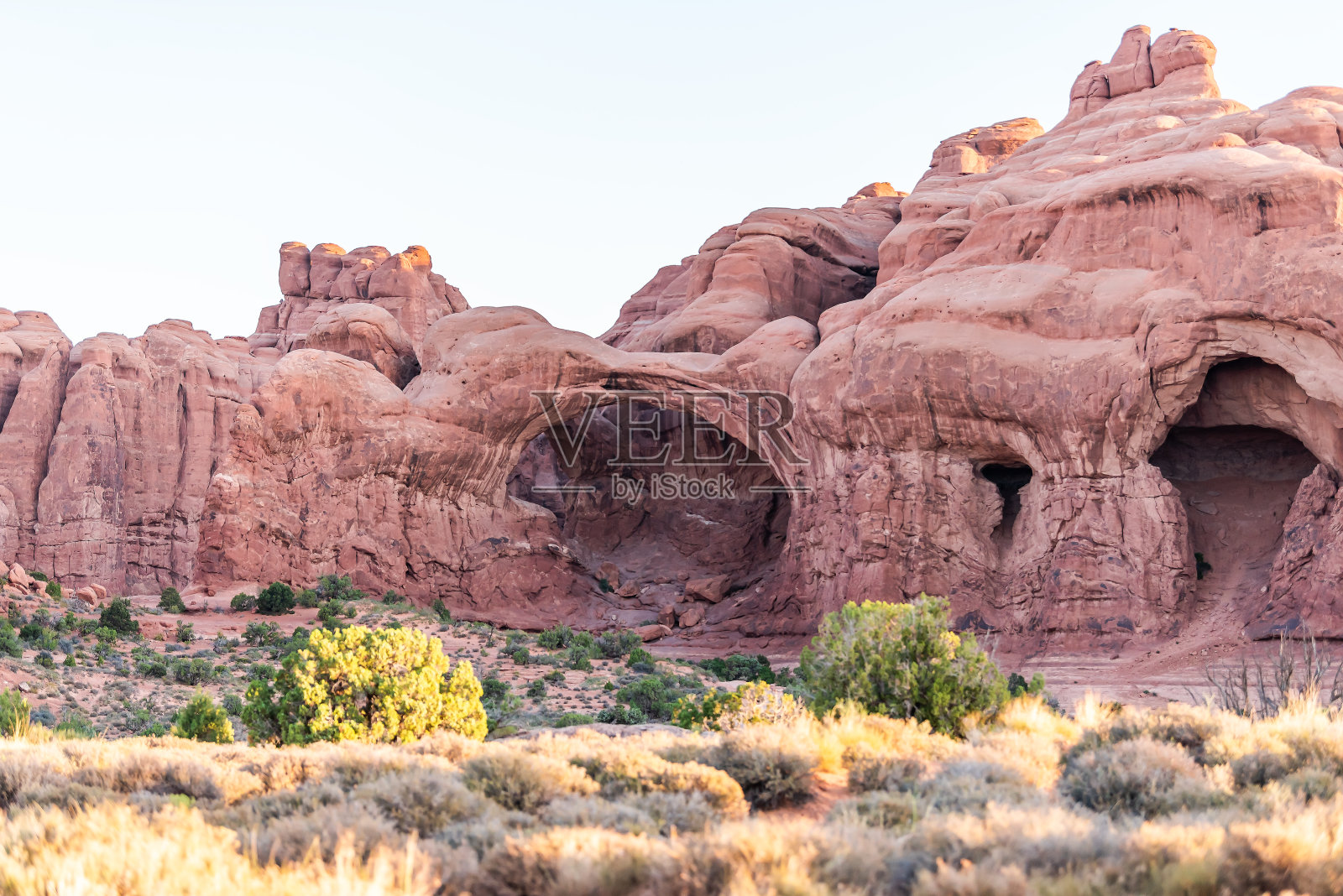 双拱在犹他州拱门国家公园以其独特的形成而闻名于世，在清晨日出时岩石的颜色呈红粉色照片摄影图片