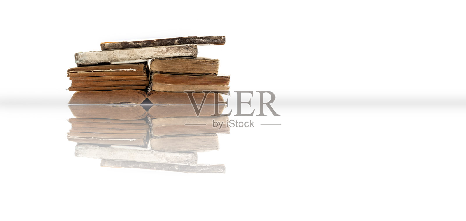 古老的书籍堆叠在一起，孤立在白色的反射上。照片摄影图片