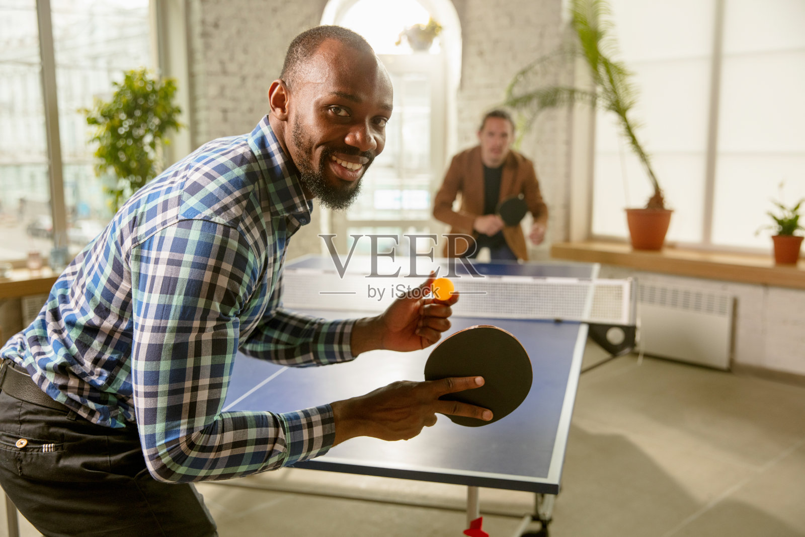 年轻人在工作场所打乒乓球，寻开心照片摄影图片