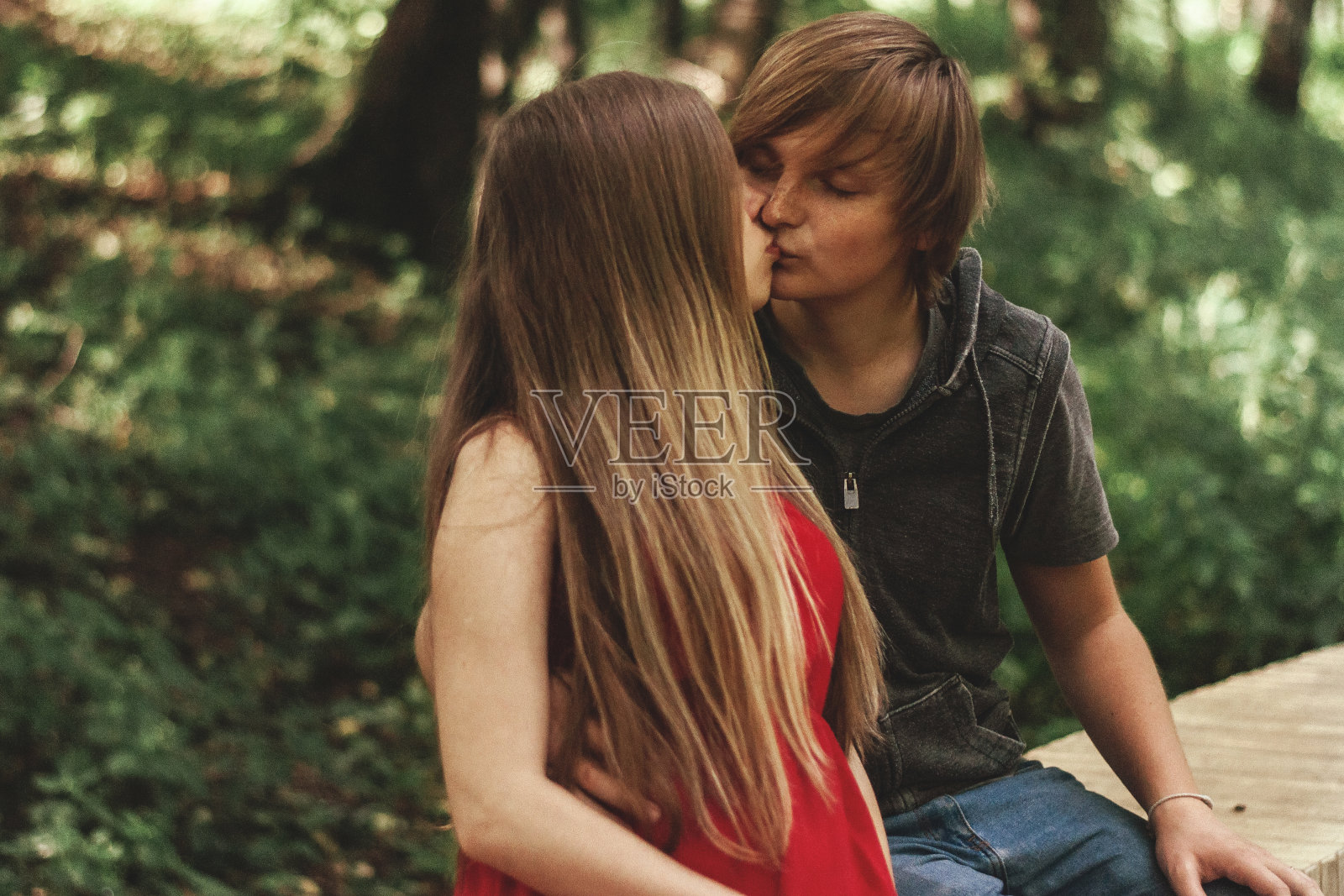 幸福的已婚夫妇丈夫拥抱美丽的成年怀孕妻子，在公园里散步。孕中期。他把手放在她的肚子上。怀孕期间散步的好处，健康护理。微笑和亲吻照片摄影图片