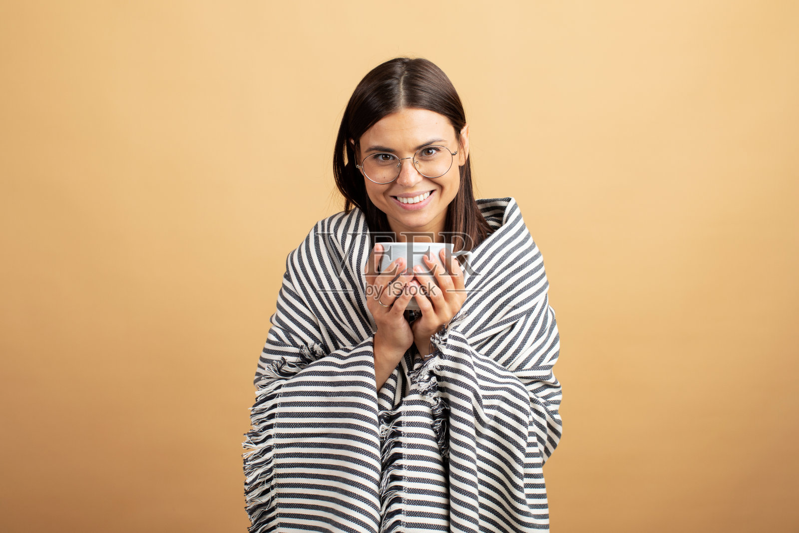 年轻女子用毯子包着喝咖啡。年轻女子感觉舒适照片摄影图片