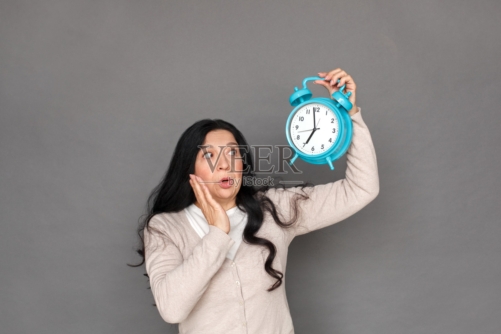 自由泳。成熟的女士孤立地站在灰色的闹钟上看着时间的震惊照片摄影图片