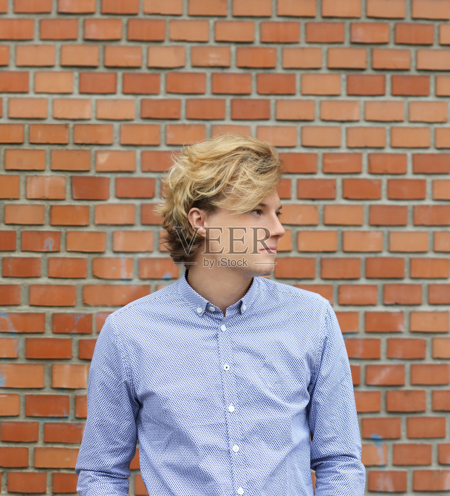 一个少年站在砖墙旁边照片摄影图片