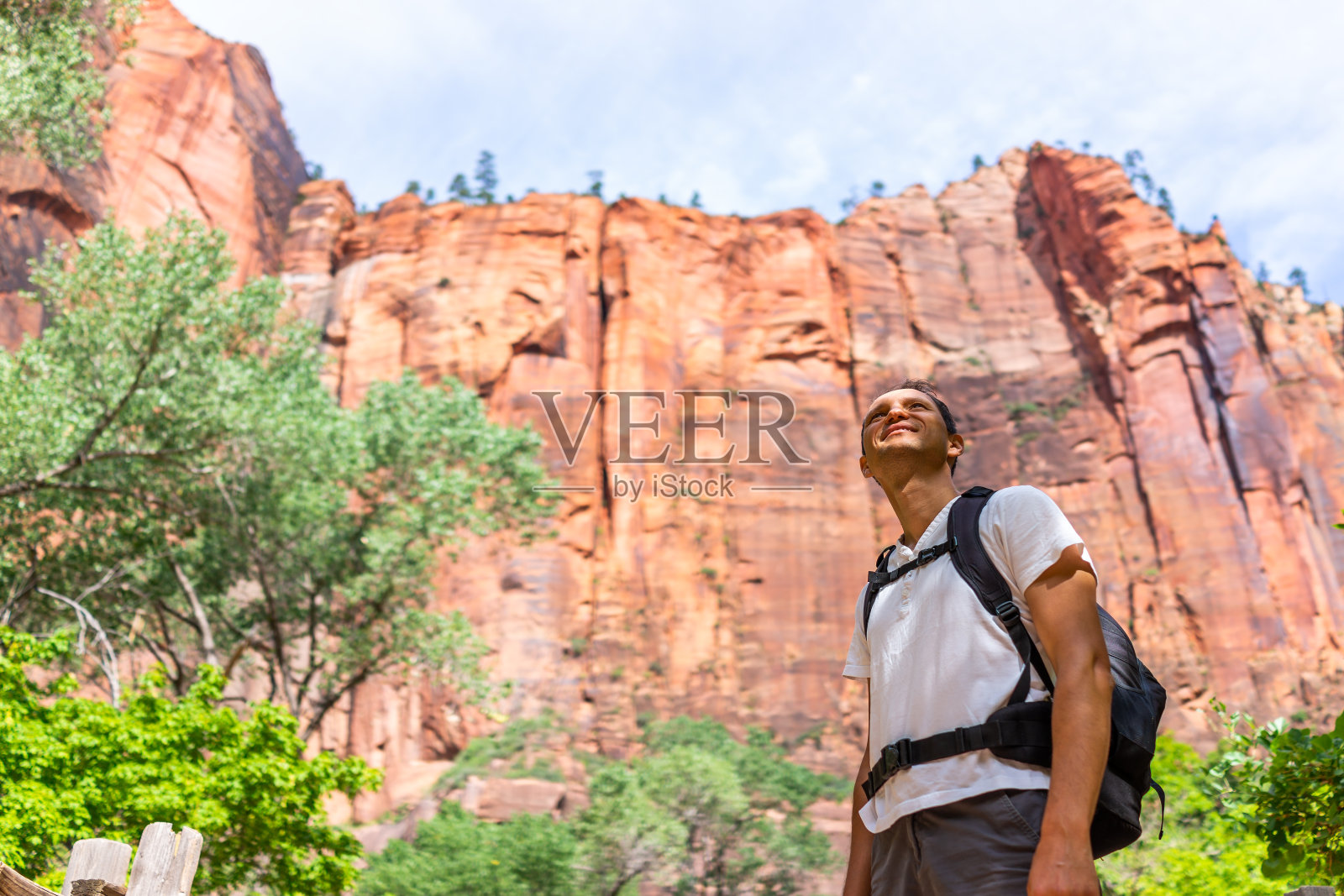 锡安国家公园滨河步道在犹他州与男子徒步旅行者仰头与背包在红色峡谷悬崖形成徒步狭窄照片摄影图片