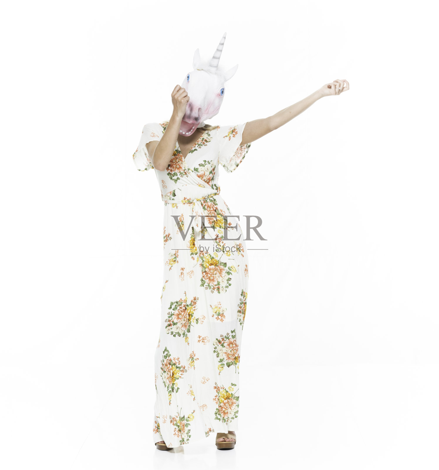 正面视图/看相机/全长20-29岁的成年金发/长发白种人年轻女性站在白色背景前戴着面具-伪装/连衣裙/长裙谁是奇怪的/戴着独角兽面具/马照片摄影图片